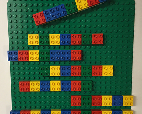 Fargete Legoklosser som er plassert i et mønster på en grønn legoplate