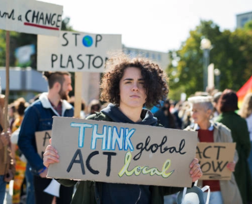 Jente som holder en plakat med teksten 'think global, act local'